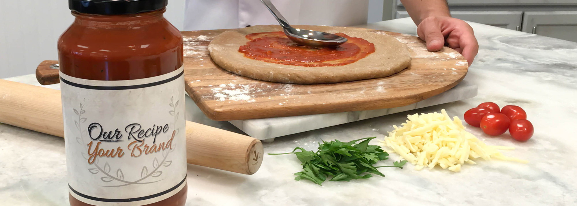 Private Label sauce bottle with chef spreading sauce on pizza
